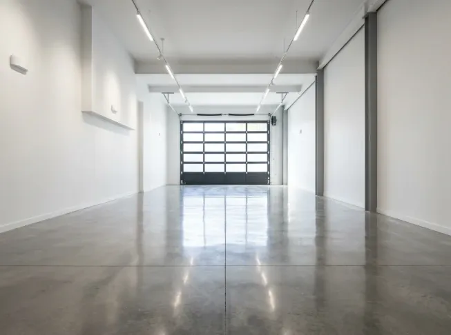 A spacious, empty luxury storage bay with polished concrete floors and white walls shown from a low depth perspective. 
